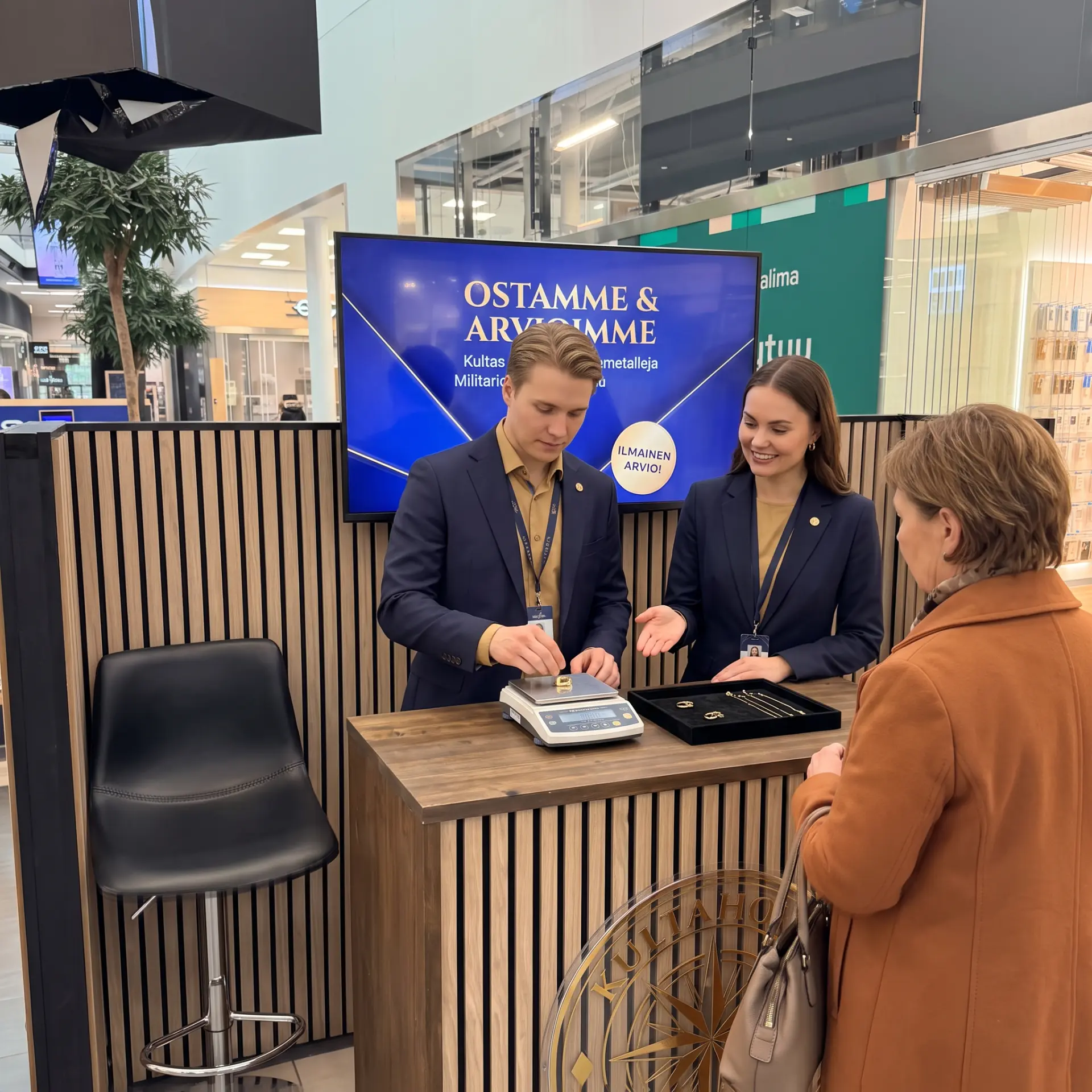 Kultaholvin ostaja punnitsee asiakkaan korua kauppakeskusständillä